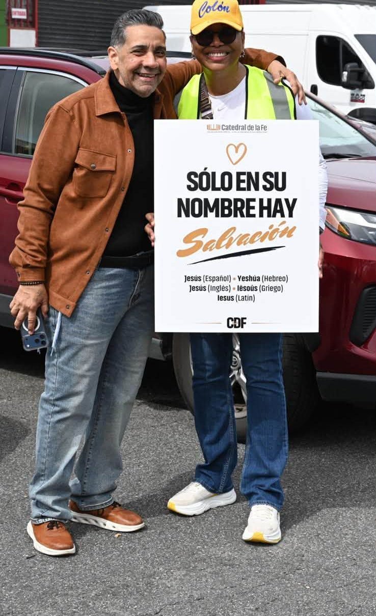 Voluntaria con el Pastor Walter y el letrero Sólo en su nombre hay salvación